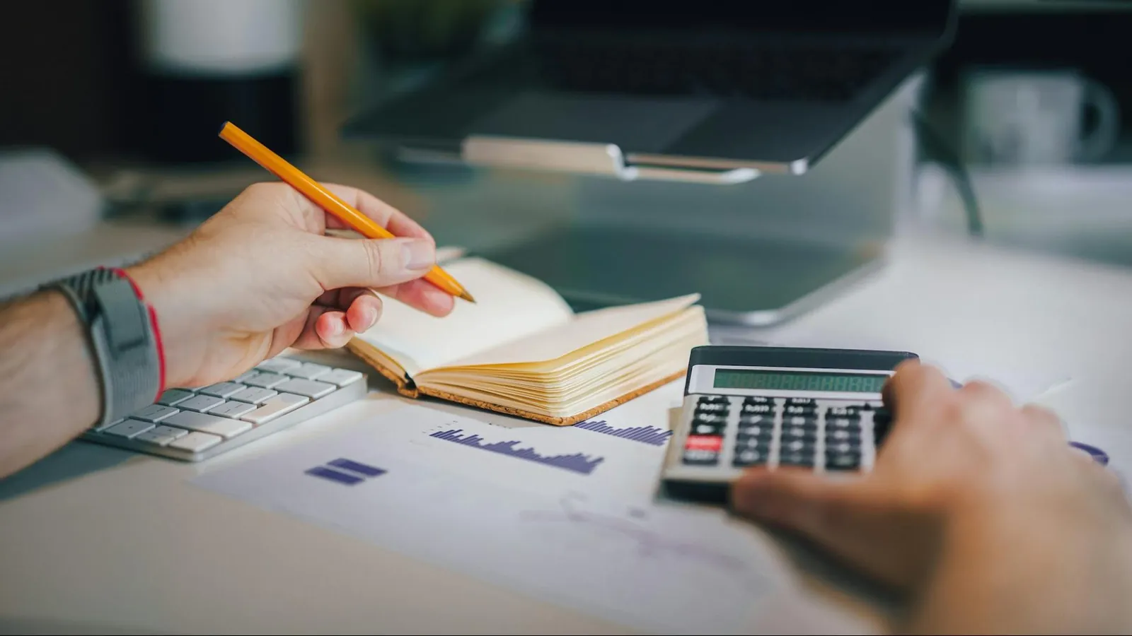 Consultant analysant un dossier de crédits d'impôt avec une calculatrice, un ordinateur et un cahier.
