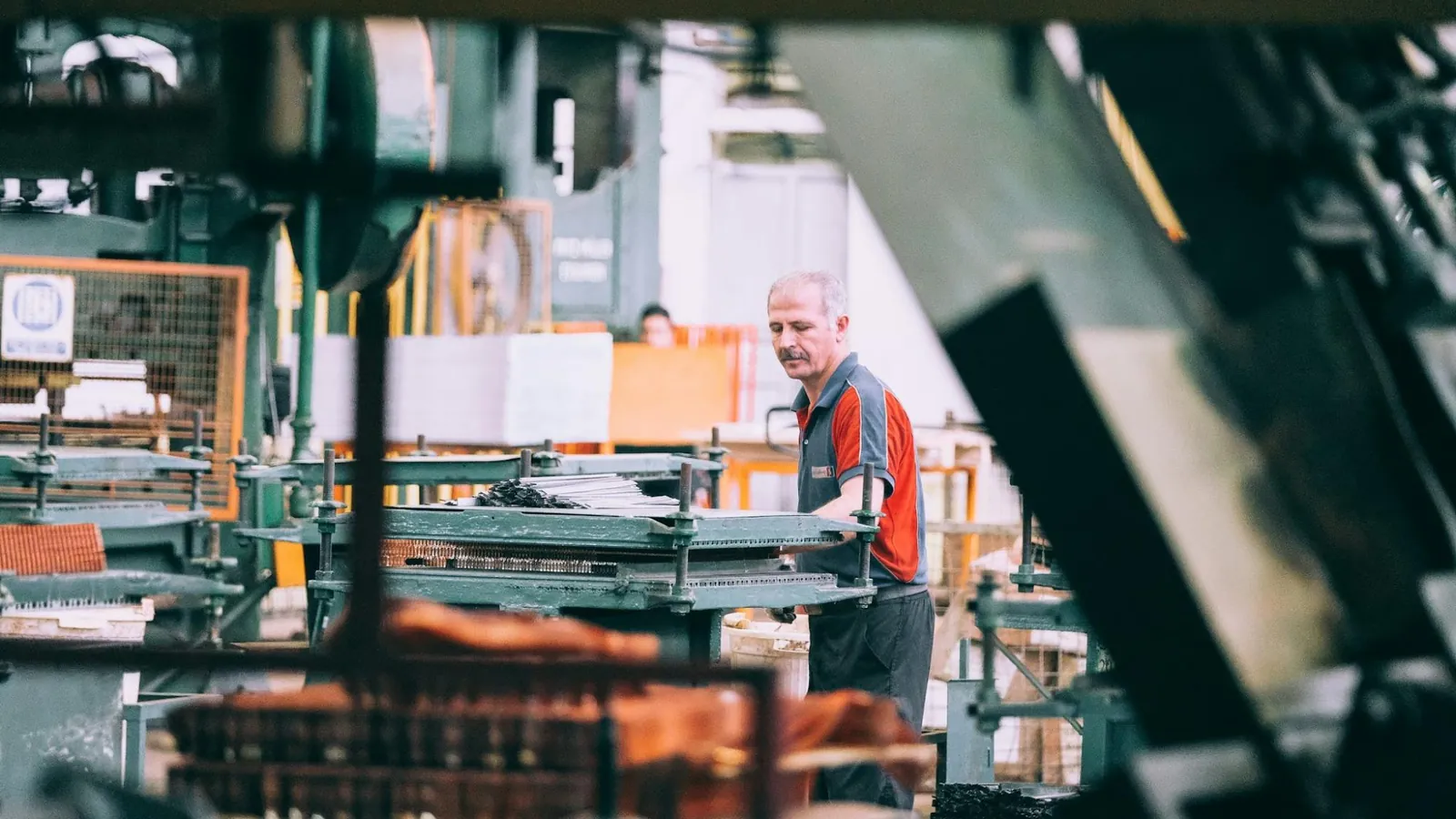 Employé d'une PME manufacturière devant une machine de production lors de l'analyse d'un projet admissible aux subventions.