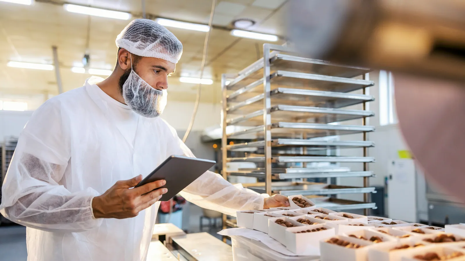Employee checking products on a tablet in a plant, a project covered by food processing grants