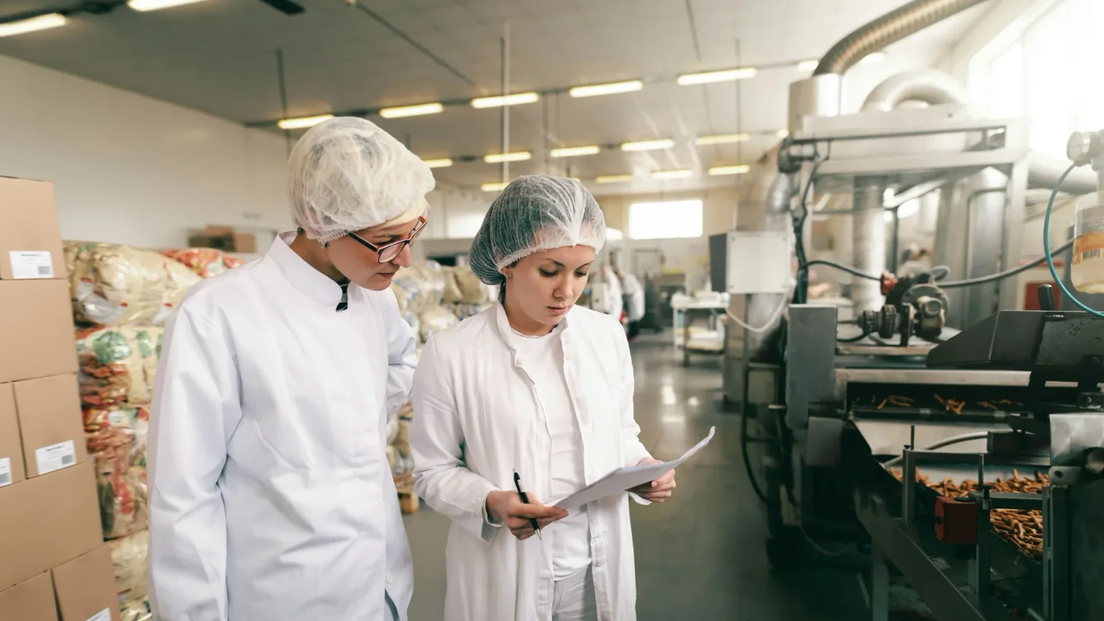 Employees reviewing a quality-control document in a food plant.